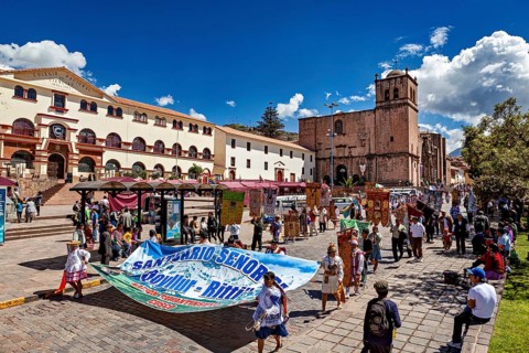 Bustling square with people and a church in the background, traditional parade of festival groups