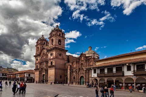 Magnificent church on a large square, lively with people and surrounded by numerous clouds, The