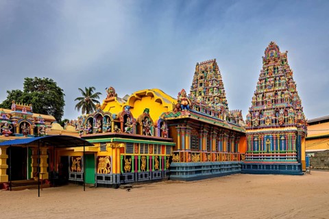 Hindu temple with colorful sculptures and traditional architecture under clear skies, The Sri