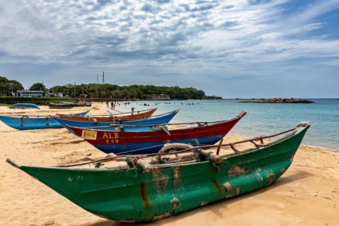 Beach with colorful fishing boats in the sand against a cloudy sky and calm sea, Traditional boats