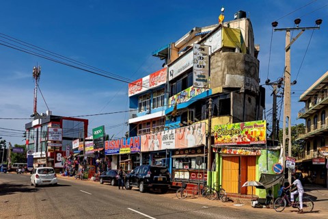 Busy urban street with shops and advertising signs under clear skies, the city of Trincomalee in