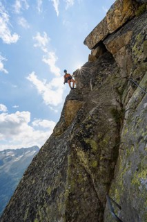 Female mountaineer on steep rock face on the secured via ferrata Krokodil-Bergsee am