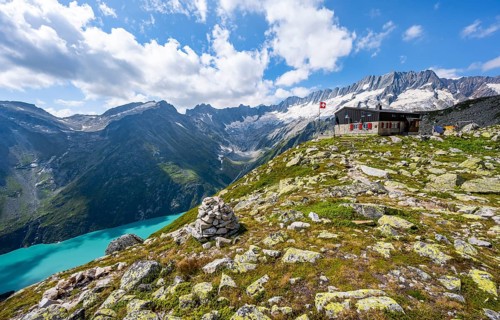 Mountain hut Bergseehütte with Swiss flag in picturesque mountain landscape, view of Damma Glacier