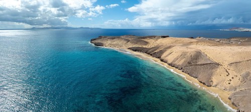 Coast with Playa Caleta del Congrio beach and blue sea, arid landscape of Los Ajaches Natural Park,