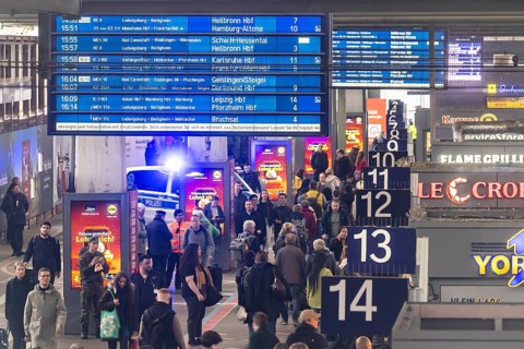 Travelers at the main train station, passengers and departure board at Stuttgart main station.