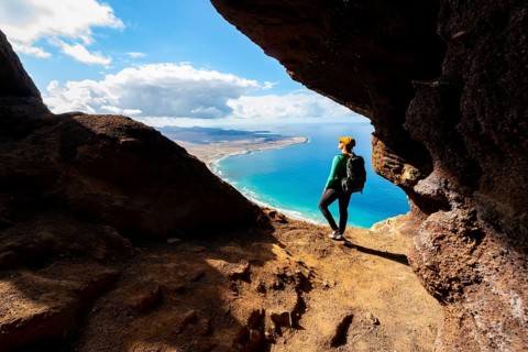 Tourist in the Cueva de las Cabras cave, young woman enjoying the view from the Risco de Famara
