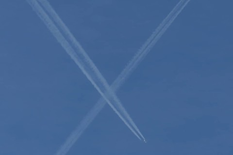 Aircraft contrails or vapour trails crossing in a blue sky, England, United Kingdom