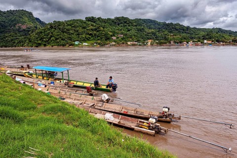 Wooden boats with motors on the banks of a river surrounded by hills, longboat on a river near