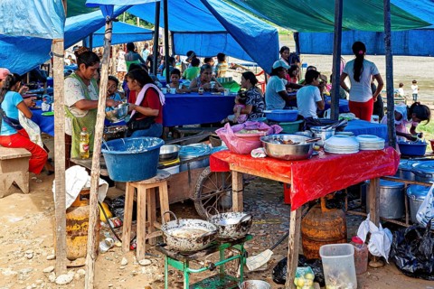 Market kitchen with people cooking and preparing food under blue tents, The market of Rurrenabaque
