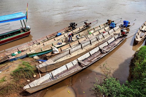 Person on wooden longboats on the banks of a quiet river, longboat on a river near Rurrenabaque in