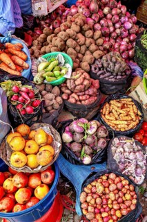 Colourful market image with a variety of fresh fruit and vegetables, including potatoes, onions and