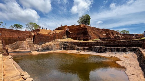 An ancient water reservoir amidst archaeological ruins under a vivid sky, The Temples, Dagobas, and