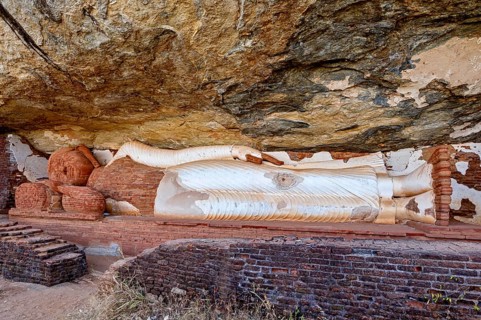 Reclining Buddha embedded in a rock wall, made of sandstone, peaceful and meditative atmosphere,