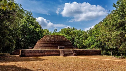 An old brick stupa surrounded by thick greenery and a cloudy sky, the temples, dagobas, and pagodas