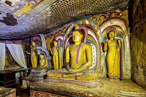 Meditative Buddha statues in a colorful cave with spiritual paintings on the walls, The cave