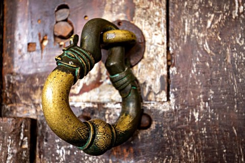 Antique brass door knocker on weathered wood, conveys a nostalgic and historic charm, door handle