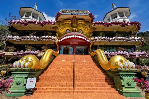 Entrance to a temple with a large golden sculpture and stone stairs decorated with ornaments, The