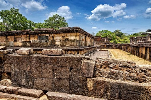 Massive ancient stone walls at a ruined site under a blue sky, The Temples of Polonnaruwa in Sri