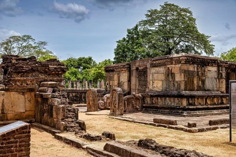 Old stone buildings in a ruined site with trees and blue sky in the background, The temples of