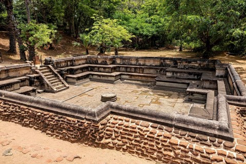 Water basin framed by stones in a wooded setting when the sun is shining, The temples of