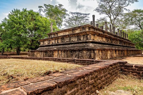 Stone plate with engravings surrounded by trees under a partly cloudy sky, The temples of
