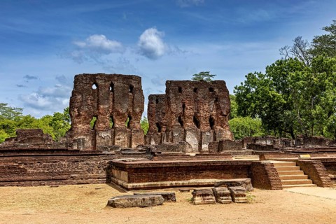 Tall brick ruins with multiple openings under a cloudy sky surrounded by trees, The temples of