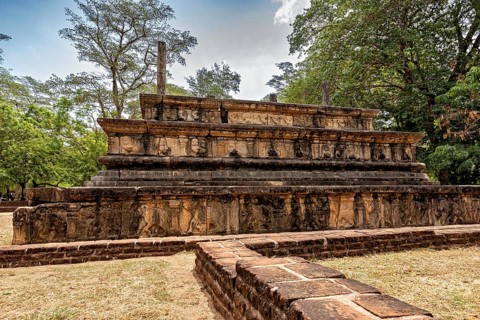 Engraved stone tablet with historical relics under a cloudy sky surrounded by trees, The temples of