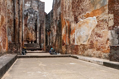Interior view of an archaeological site with large statues and brick walls, The temples of