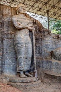 Standing rock statue with detailed texture and ancient appeal under a canopy, The Buddhas near