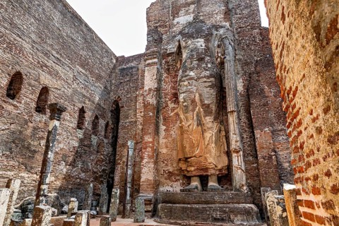 Large standing statue surrounded by ruins of old brick walls, The Temples of Polonnaruwa in Sri