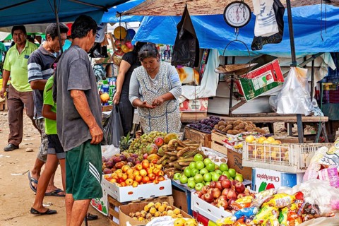 Fruit and vegetables in boxes at a market stand where customers look around and shop, The