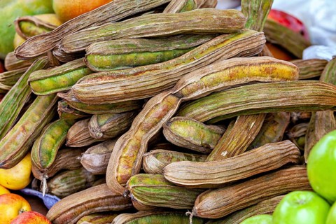 A pile of dried beans surrounded by various fresh fruits in rich colors, The fruits of the ice