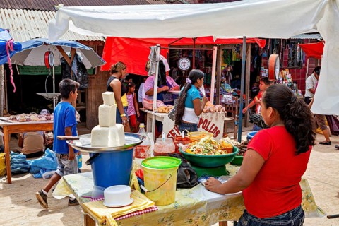 Lively market activity with people at stands under tent roofs, The Rurrenabaque market in Bolivia