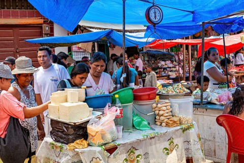 Market scene with people at a vegetable stand under colorful tent roofs, The Rurrenabaque market in