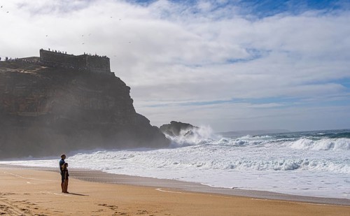 Tourists watch the waves of the Atlantic on the rocky plateau of Sito, also known as Forte São