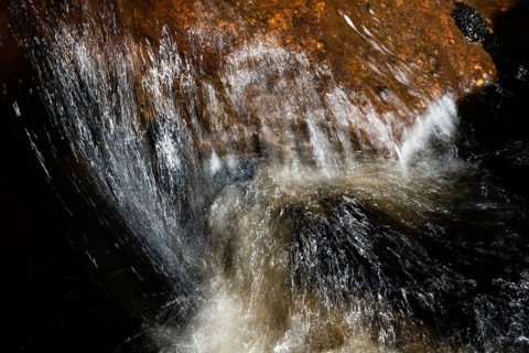 Stream flow with dark water, reflections and turbulences, long exposure, Sweden