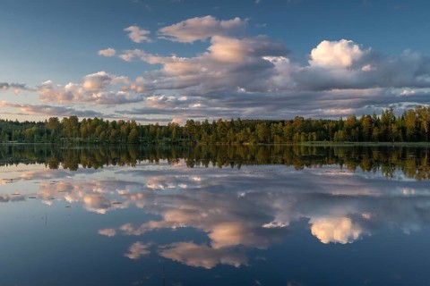 Clouds reflected on the water surface, forest lake, evening mood, at Sunne, Sweden