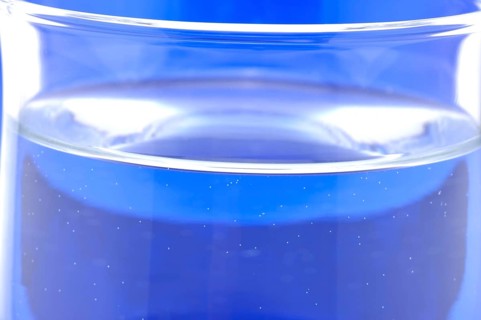 Glass with mineral water, small carbonated pearls on the edge of the glass, drinking water