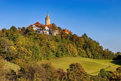A castle in a hilly wooded area, surrounded by autumn landscape and blue skies, The Leuchtenburg