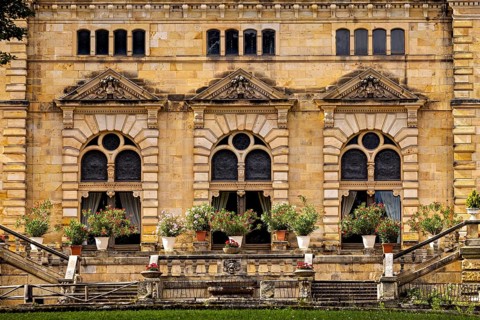 Detail of the castle façade with lush flowers in pots in front of large windows, The Hummelshain
