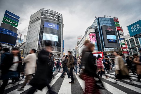 Crowd crossing zebra crossing on a large intersection, motion blur, back modern houses with