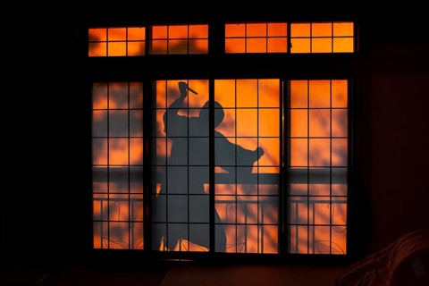 Shadow of a man, burglar with knife, assassin, ninja, on the balcony behind sliding shoji doors in