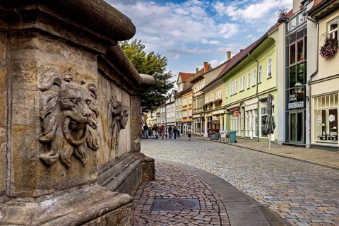 Urban street with lion head sculpture and historic architecture, animated by people, The old town