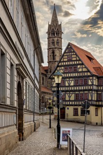 Alley with a view of a half-timbered house and a church tower, under a cloudy sky, the old town of