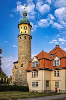 Large tower with clock and house with red roofs against cloudy sky, The Niedeck Ruins in Arnstadt