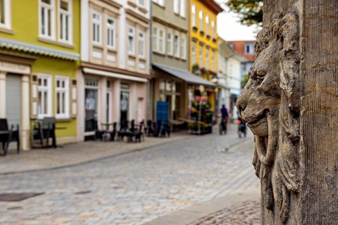 Stone lion relief in front of picturesque old town street with colorful houses, lion head at the