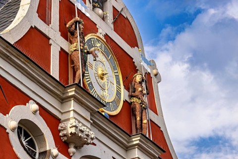Baroque façade with clock and figures under a blue sky with clouds, The old town of Arnstadt in