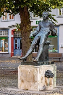 Seated bronze statue of a man under a tree in a city, Johann Sebastian Bach monument in the old