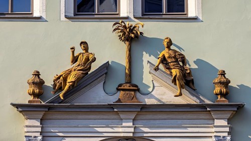 Detailed façade decoration with two statues and a decorative palm tree, statue and monument in the