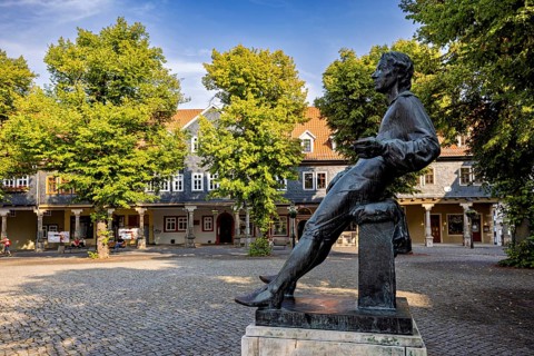 Bronze statue of a man on a paved square with trees, Johann Sebastian Bach monument in the old town